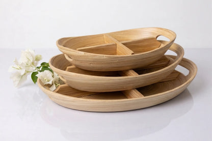 Set of three bamboo trays stacked on a white background with a small white flower.